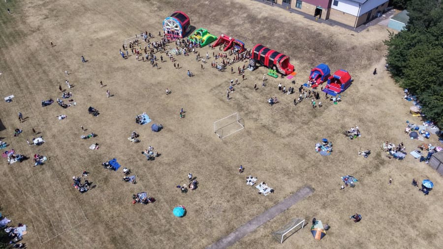 The whole school spread out across the field for the summer Family Picnic, with a row of inflatables along the top